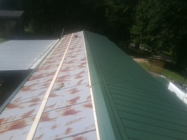 Old rusted panels beside newly installed green metal roofing — Wind Damage Roof Repair by Roofing Brothers in Pembroke