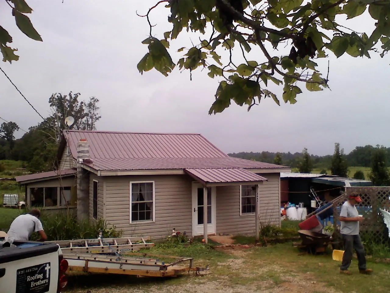 Crew finishing a mauve metal roof on a small farmhouse in Pembroke